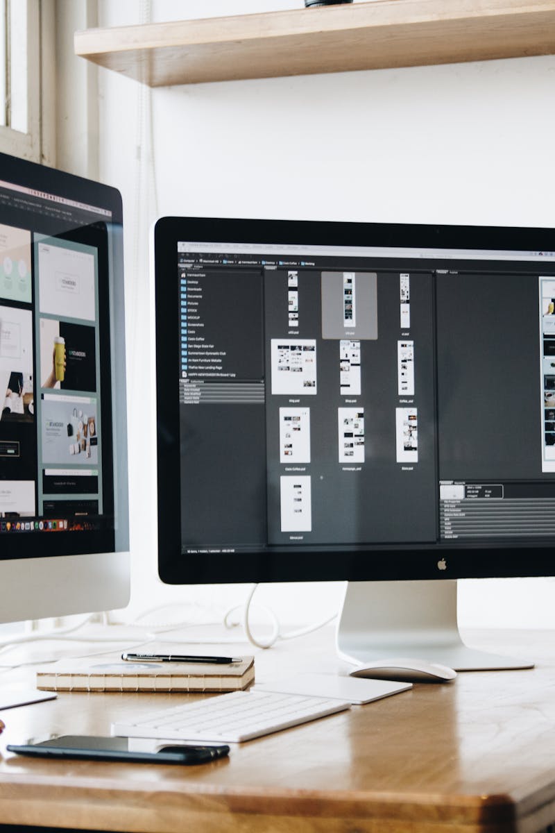 Stylish office workspace featuring dual monitors, a keyboard, notebooks, and decorative plant.